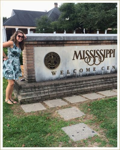 Ashleigh at the Mississippi Welcome Center sign on a cross-country road trip